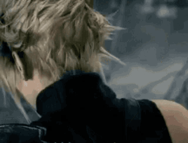 a close up of a person 's back with their head down and their hair blowing in the wind .