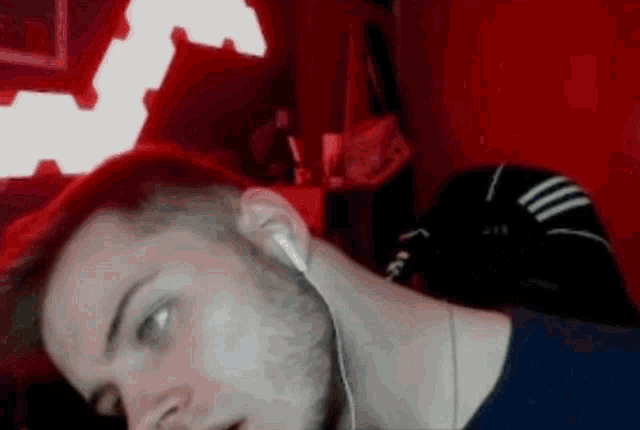 a man is wearing headphones and looking at the camera while sitting in front of a red wall .