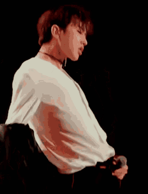 a man in a white shirt is holding a microphone on a stage