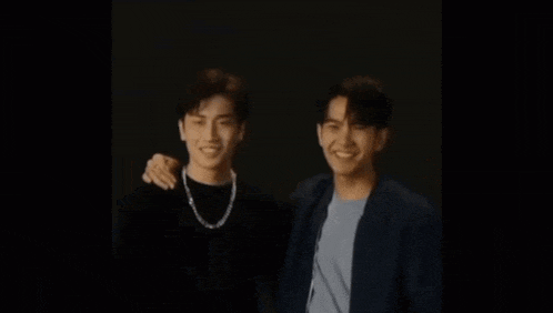a couple of men are standing next to each other and smiling .