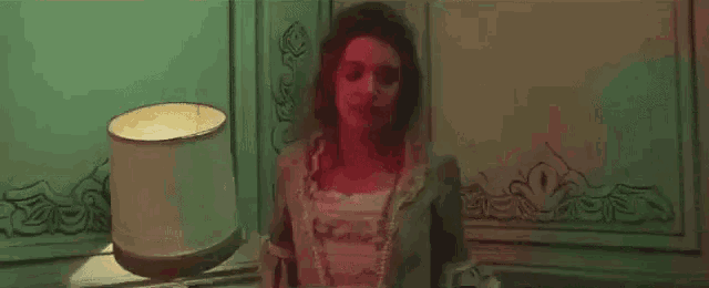 a woman is standing in front of a lamp in a room .