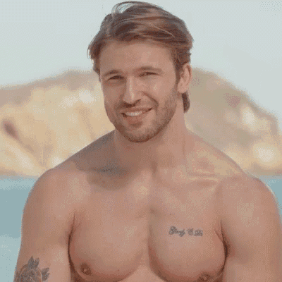 a shirtless man with tattoos on his chest is smiling .