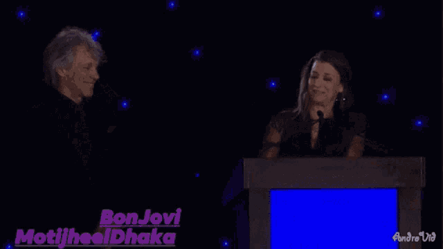 a man and a woman are standing next to each other in front of a blue screen that says bonjovi