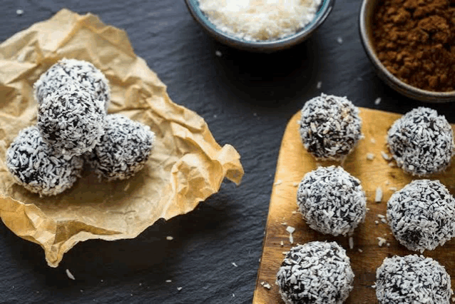 a wooden cutting board topped with coconut balls