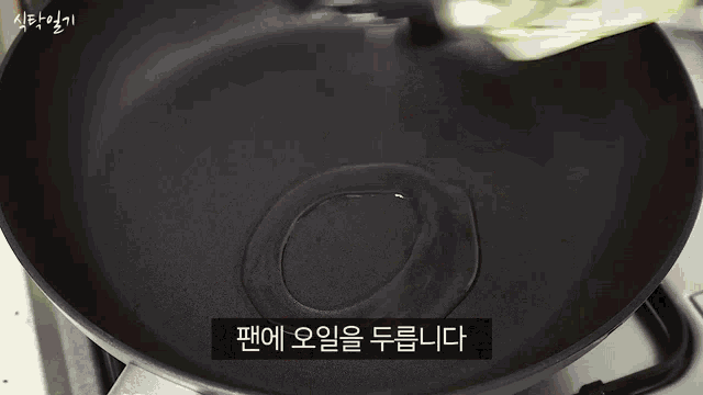 a person is cooking vegetables in a frying pan on a stove with korean writing on the bottom .
