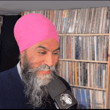 a man with a beard and a pink turban is holding a microphone