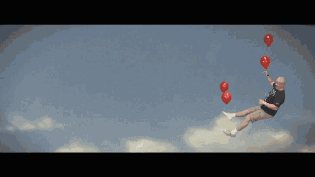 a man in a black shirt is flying through the air with three red balloons that say ' i love you ' on them