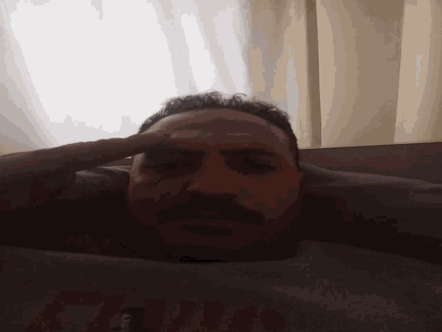 a man laying down with his hand on his forehead wearing a grey nike shirt
