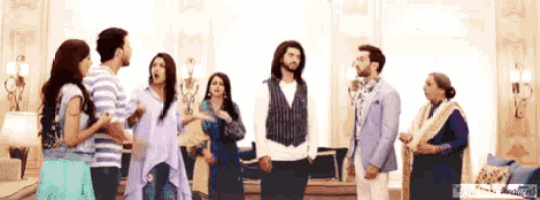 a group of people are standing in a living room with a watermark that says ' bollywood ' on it