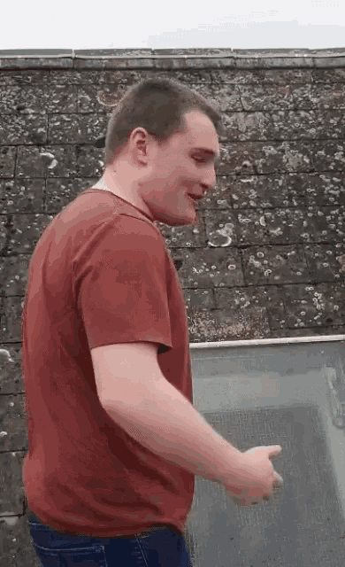 a young man in a red t-shirt is standing on a balcony .