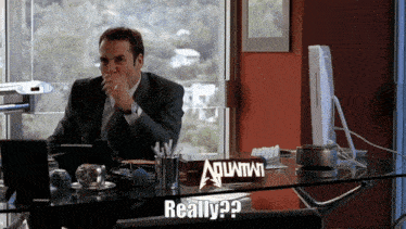 a man sitting at a desk with a sign on it that says aquafina
