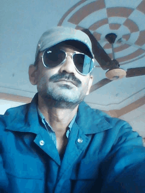 a man wearing a hat and sunglasses takes a picture of himself