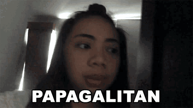 a woman in a dark room says papagalitan in white letters