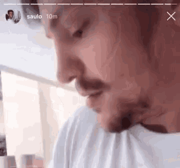 a man with a beard is wearing a white shirt and looking down .