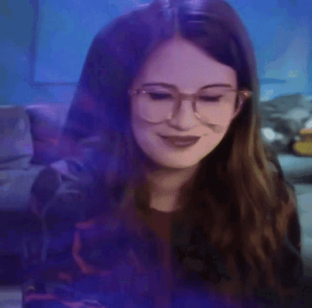 a woman in glasses is standing in front of a couch
