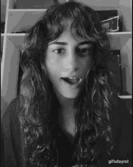 a black and white photo of a woman with long curly hair making a funny face