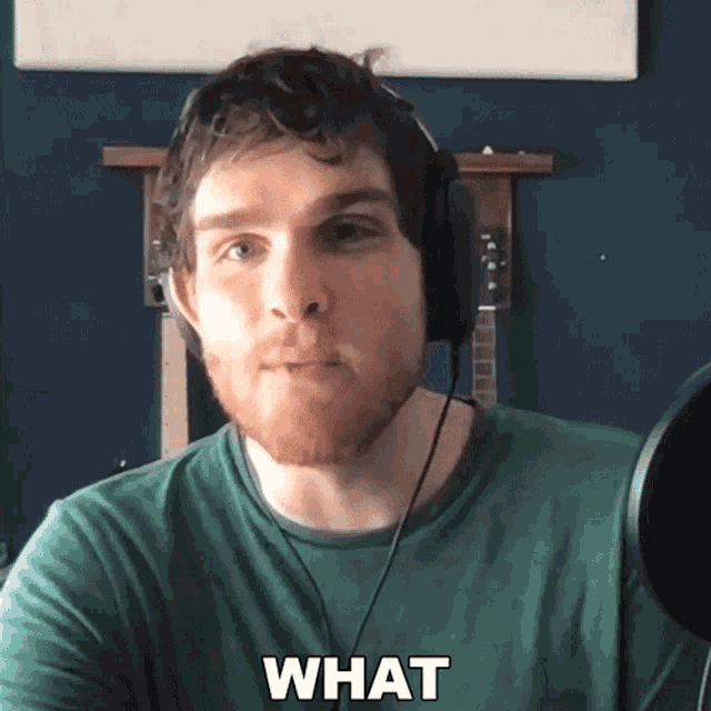 a man wearing headphones and a green shirt says " what " in front of a microphone