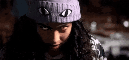 a close up of a woman wearing a purple beanie with eyes on it .