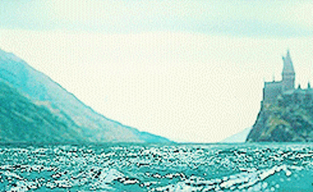 a castle is visible in the distance behind a body of water .