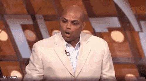 a man in a suit is yawning while standing in front of a microphone on a stage .