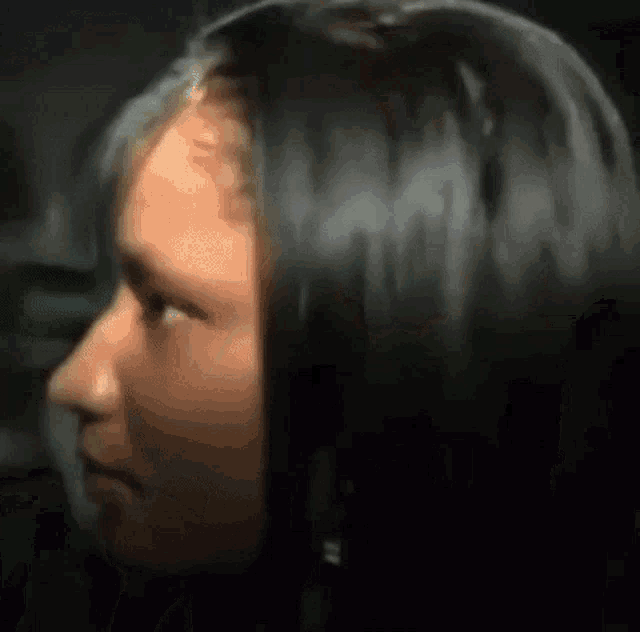 a close up of a woman 's face with long black hair and earrings .
