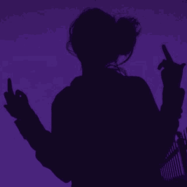 a silhouette of a woman giving the middle finger against a purple background .