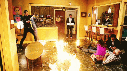 a group of people are standing around a fire in a room