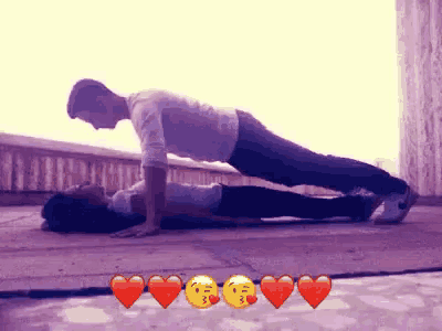 a man and a woman are doing push ups on the ground with hearts around them
