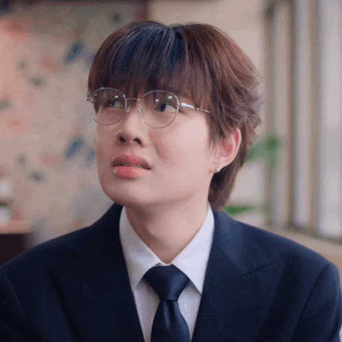 a man wearing glasses and a suit makes a face