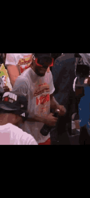 a man in a white shirt and hat is standing in a crowd .