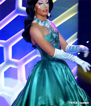 a woman in a green dress and white gloves is on a stage .