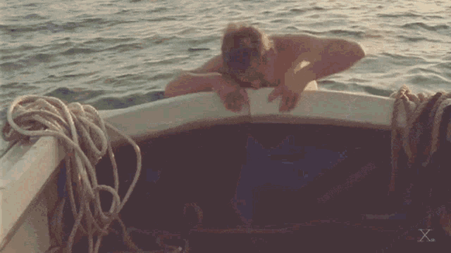 a shirtless man in a boat with a x on the bottom of the image