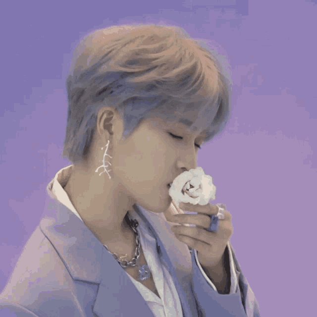 a man with a flower in his mouth wearing a purple suit