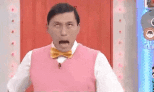 a man is wearing a pink vest and a yellow bow tie .