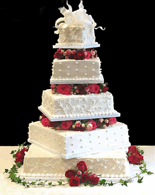 a white wedding cake with red roses and pearls