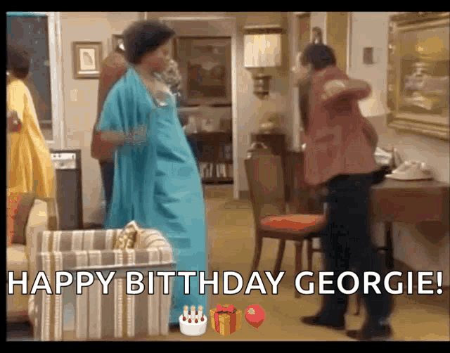 a woman in a blue dress is dancing in a living room while a man in a red jacket looks on .