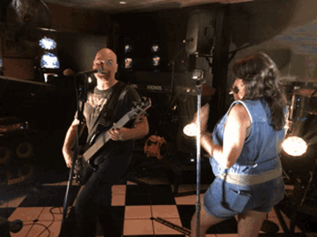 a man singing into a microphone while a woman plays guitar