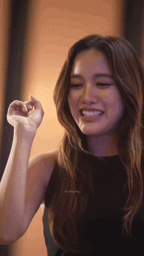 a woman in a black dress is smiling and making a funny face
