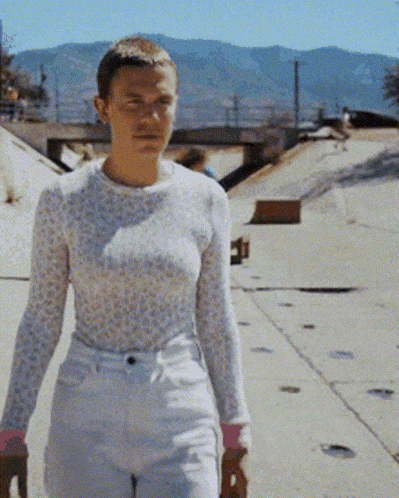 a woman in a white top and white shorts is walking down a sidewalk .