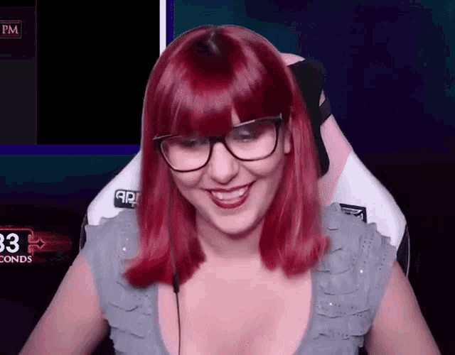 a woman with red hair and glasses is smiling in front of a screen that says pm
