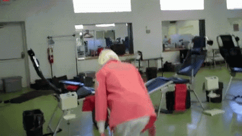 a woman in a red jacket is standing in a room with a red exit sign on the wall