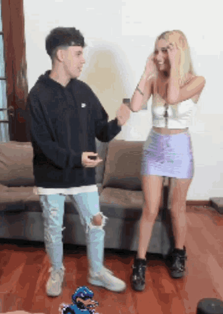 a woman in a purple skirt stands next to a man in a black hoodie