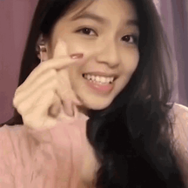 a close up of a woman making a heart shape with her hands