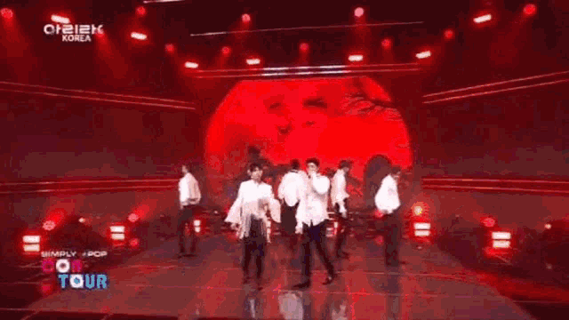 a group of young men are standing on a stage and singing into microphones .