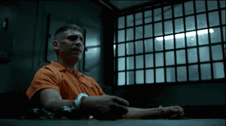 a man in an orange shirt sits in a dark room