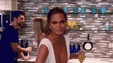 a woman in a white dress is holding a glass of orange juice .