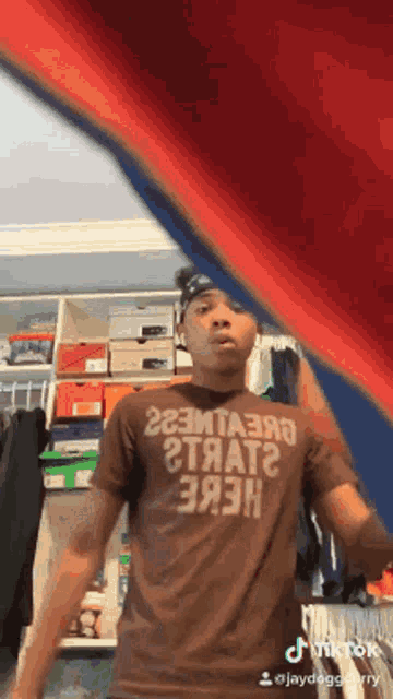 a man wearing a t-shirt that says " here " is standing in a closet