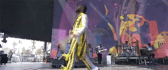 a man in a yellow and black striped outfit is walking on a stage