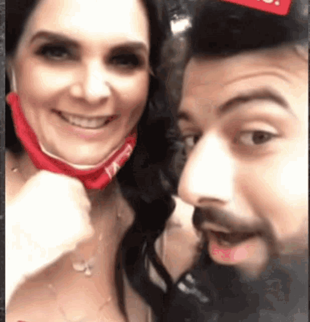 a man and a woman are posing for a picture together . the woman is wearing a red bandana .