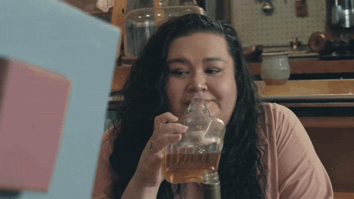 a woman in a pink shirt is drinking from a glass